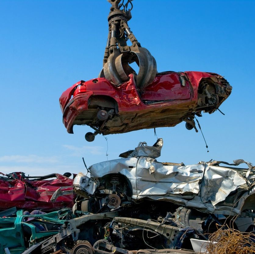 gancho de grua apresando coche rojo en desguace